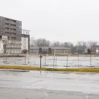 An empty parking lot with a building in the background on a rainy day.