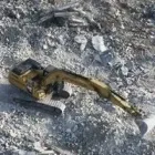 A toy excavator is sitting on top of a pile of rocks.