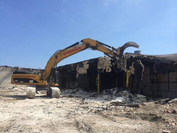 A yellow cat excavator is demolishing a building