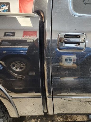 A black truck with a chrome door handle is parked in a garage.