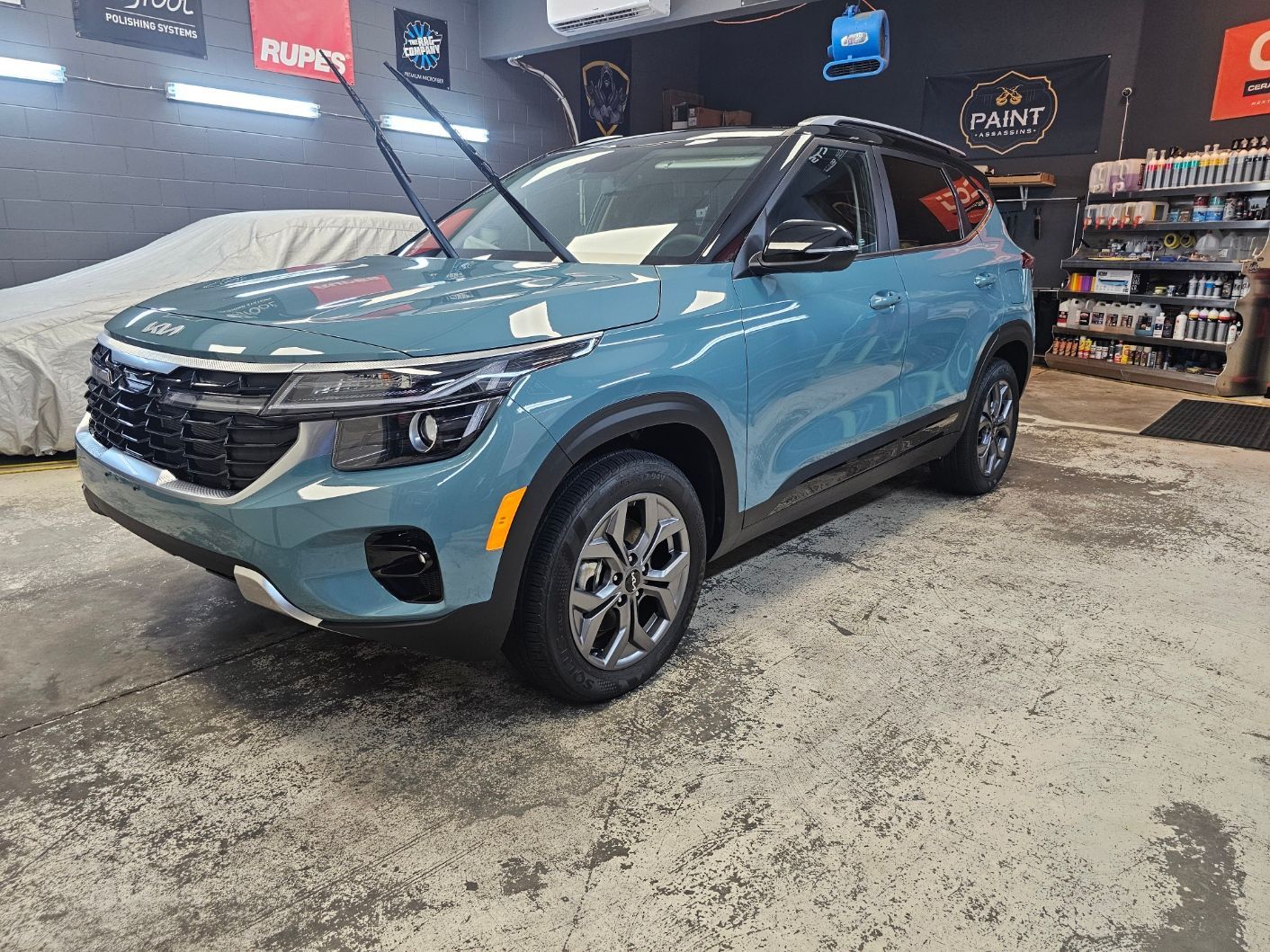 A blue car is parked in a garage.