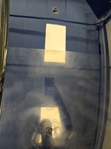 A close up of a car hood with a reflection of a person in it.