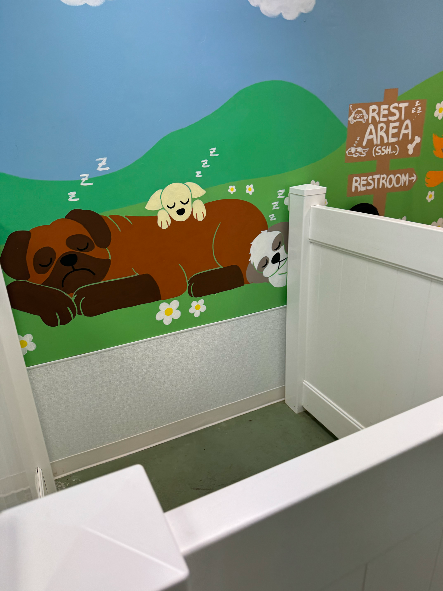 A bathroom with a painting of a dog sleeping on the wall.