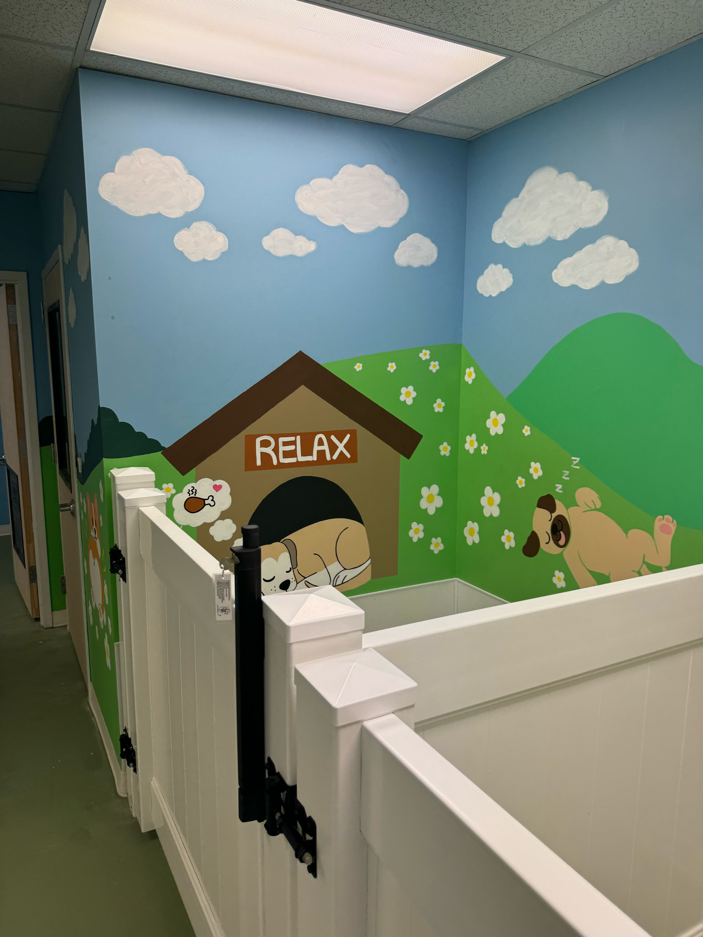 A dog house with a fence and a painting of a dog on the wall.