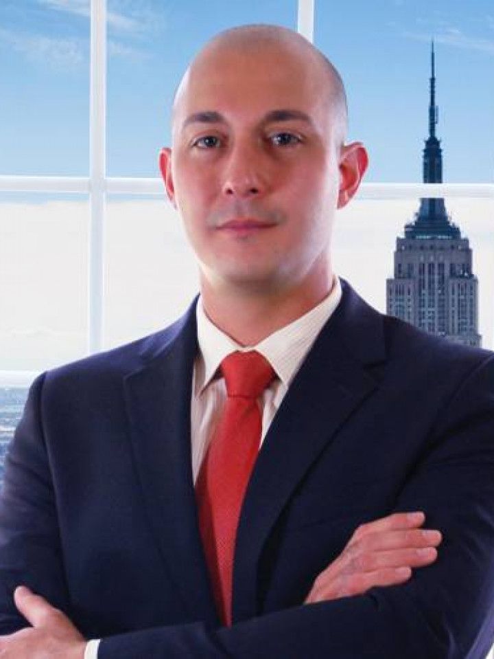 A man with a beard is wearing a suit and white shirt.