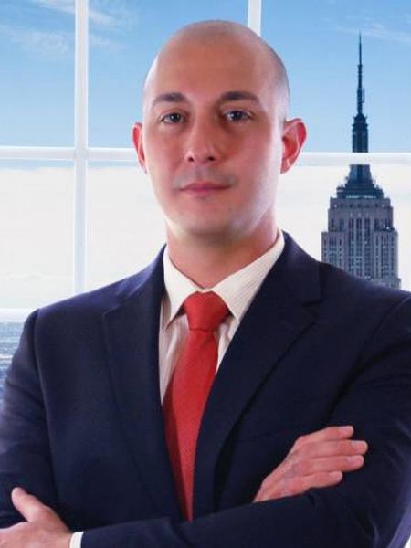A man with a beard is wearing a suit and white shirt.