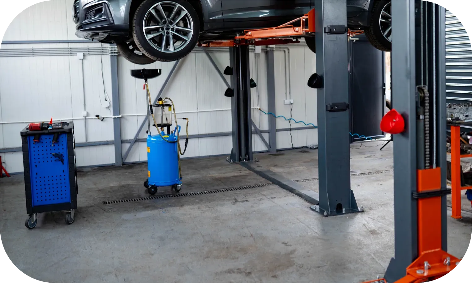 A car is sitting on a lift in a garage.