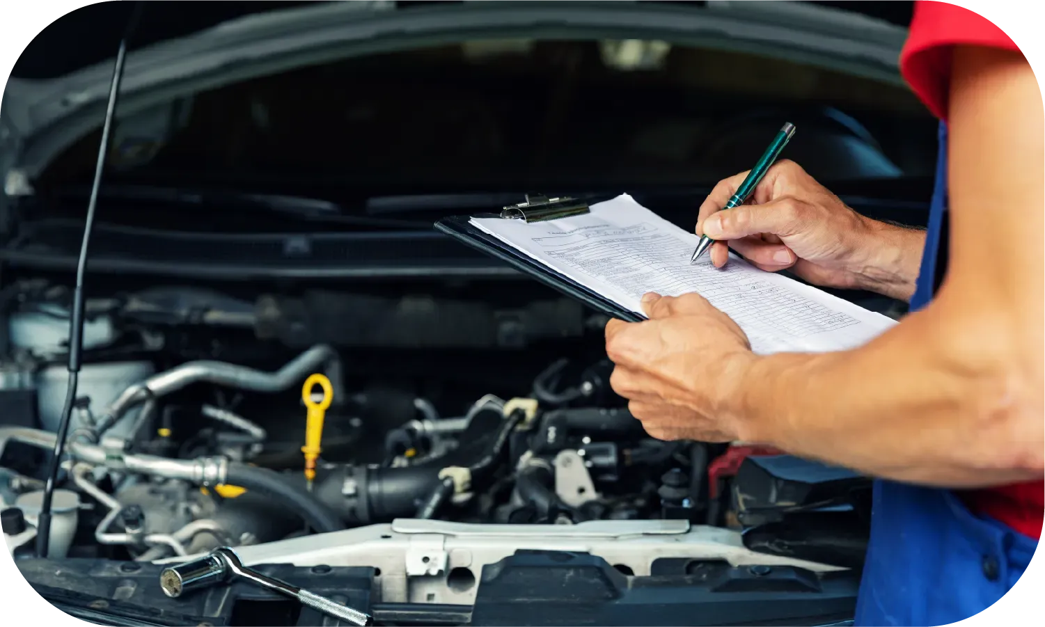 A mechanic is writing on a clipboard while working on a car.