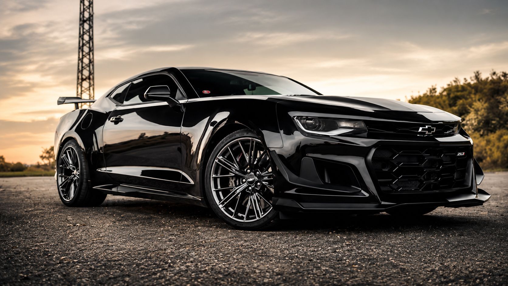Black sports car parked on pavement at sunset, with a tower in the background