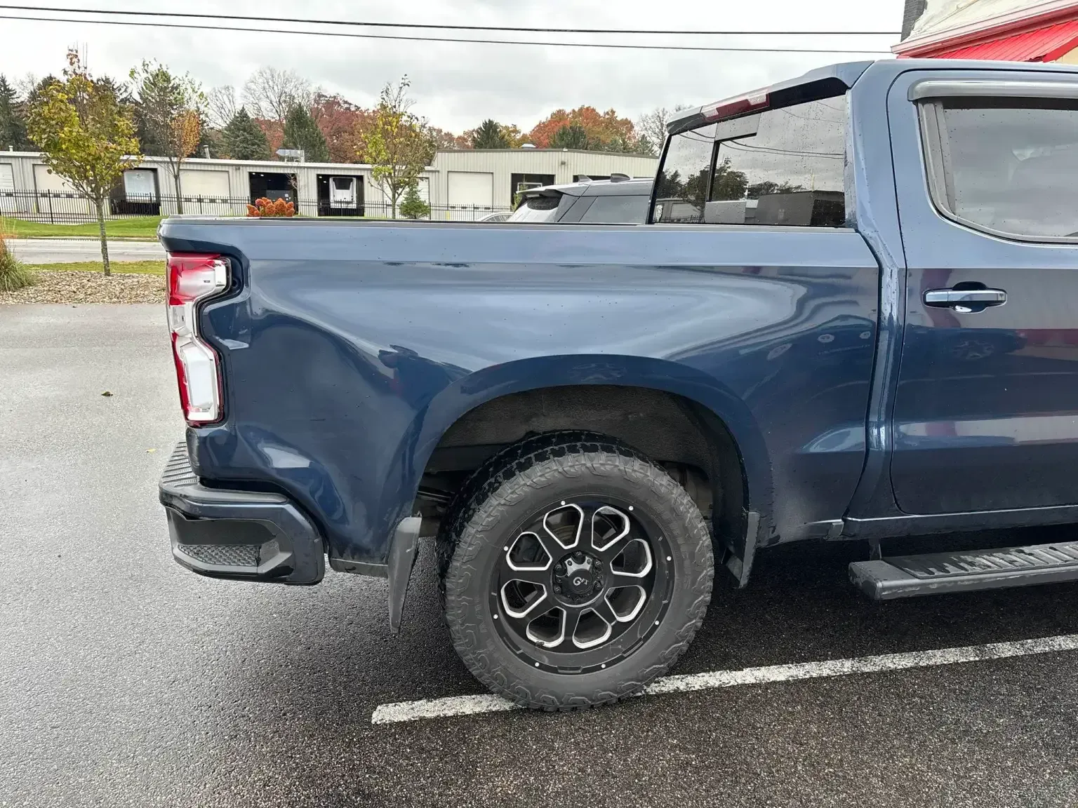 Blue pickup truck parked on asphalt. Black and silver rim.