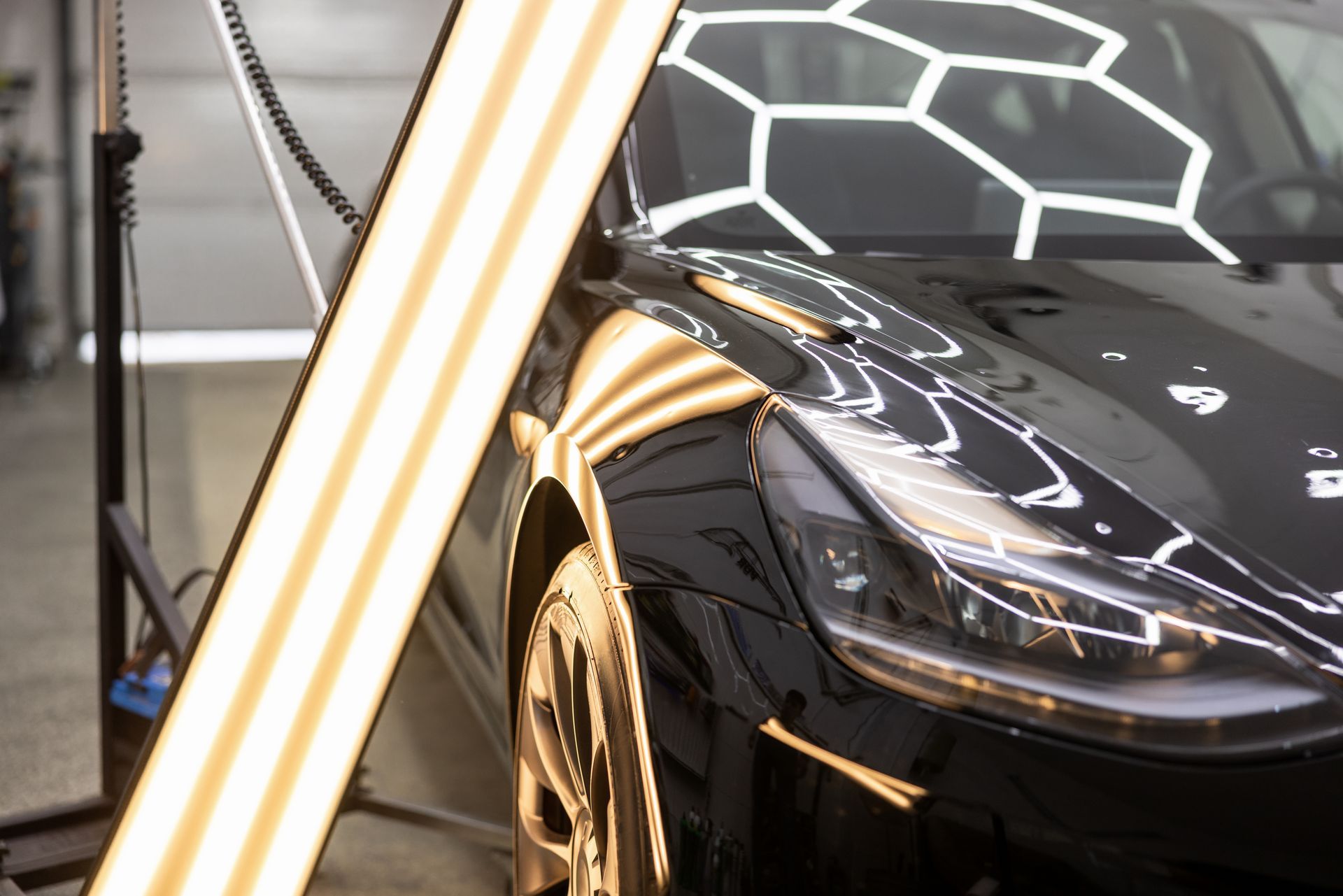 A person polishing a red car with a power tool, the car is taped in sections. A person polishing a red car with a power tool, the car is taped in sections.