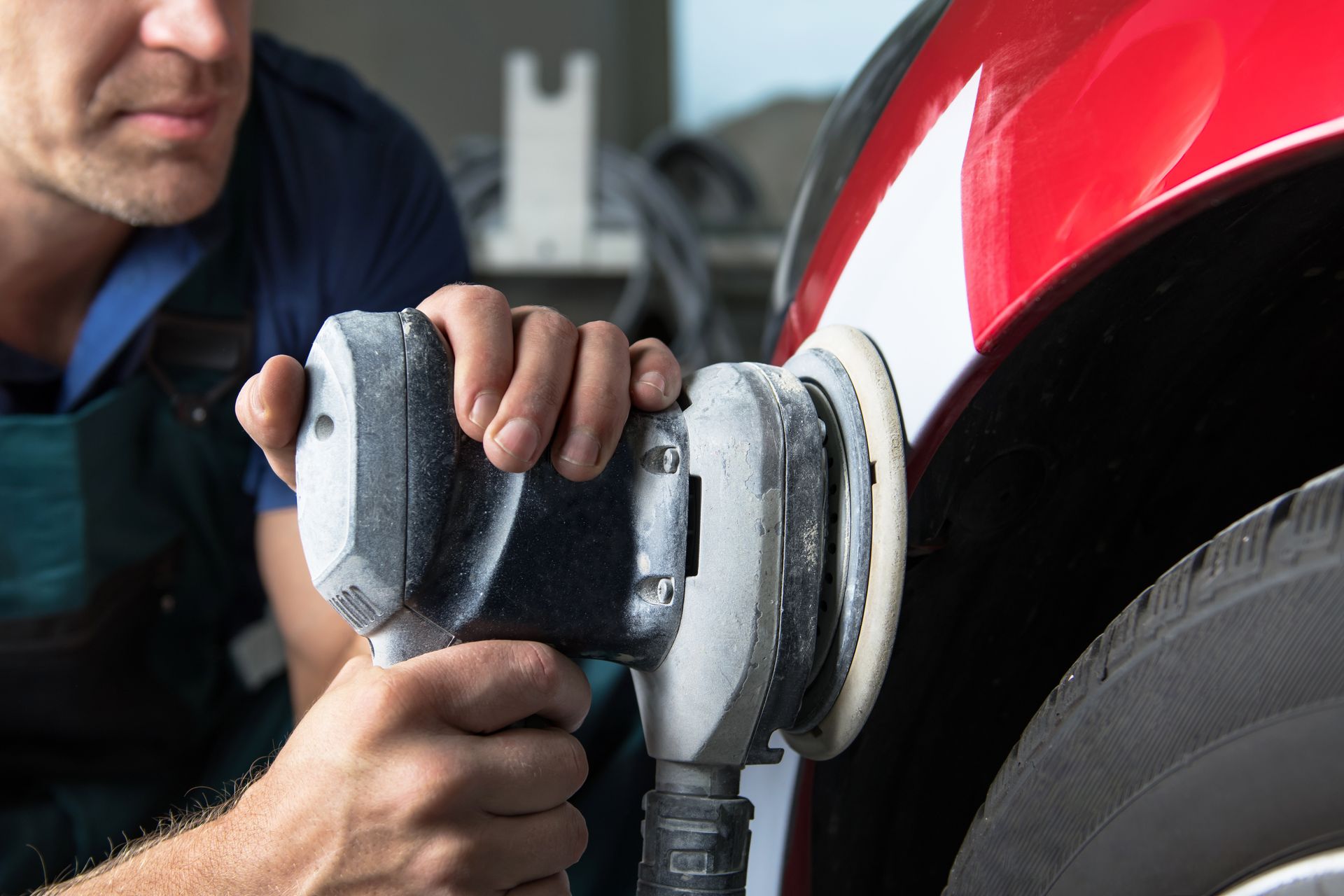 Close-up of sanding a vehicle panel during a collision repair and paint preparation process.