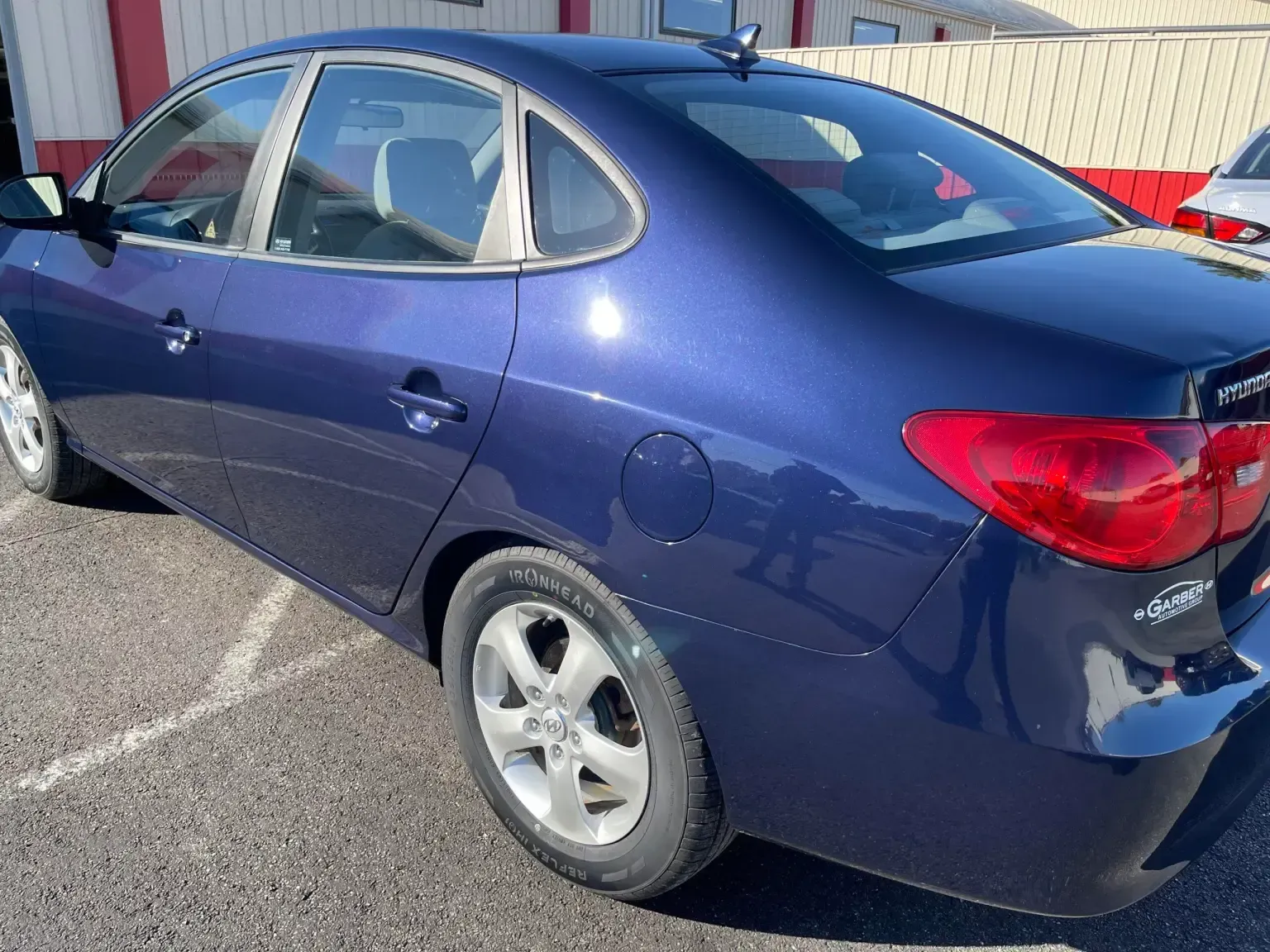 Blue sedan parked outdoors with sunlight reflecting off the paint.