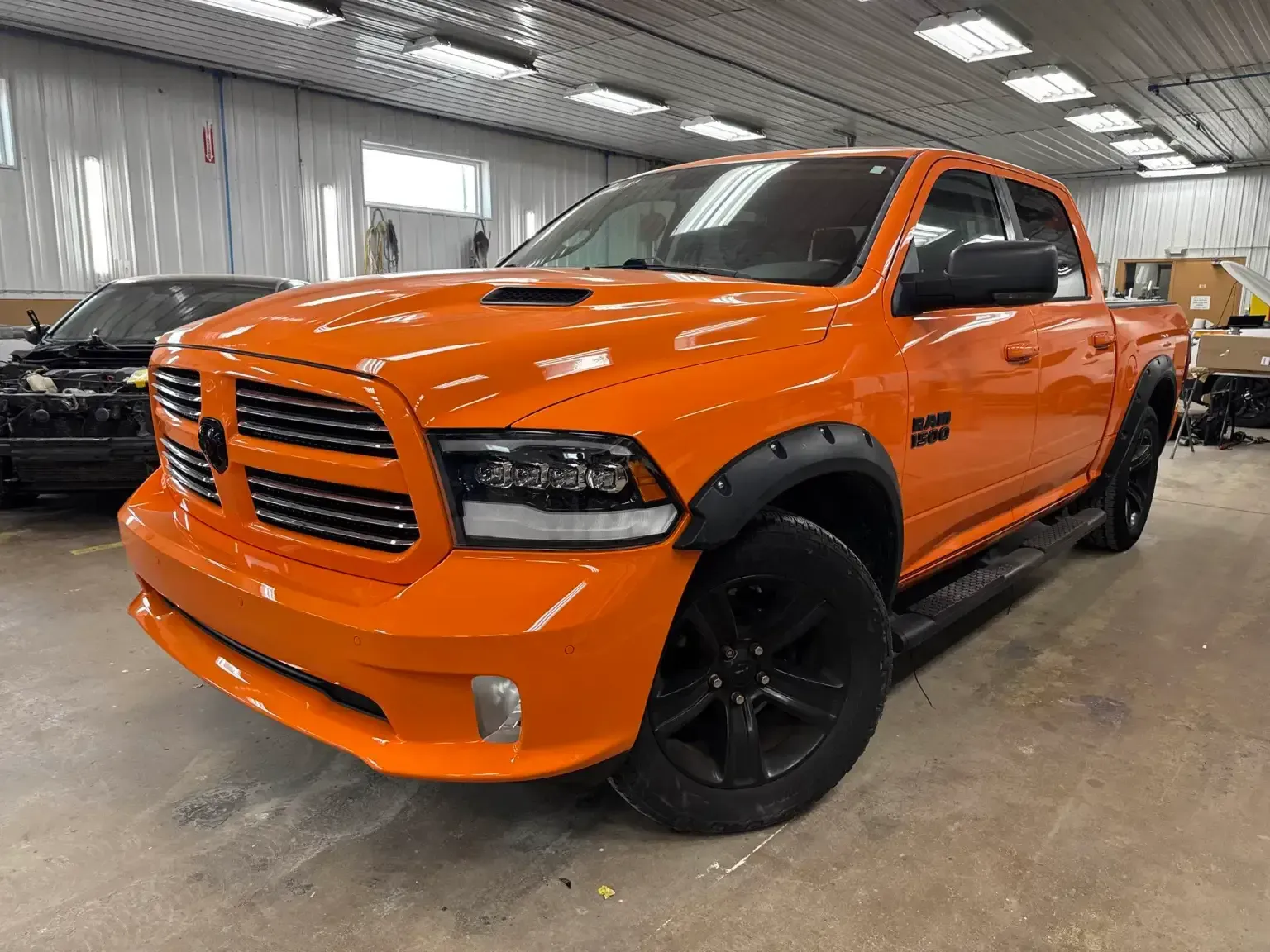 Orange Ram truck with black accents, parked indoors.