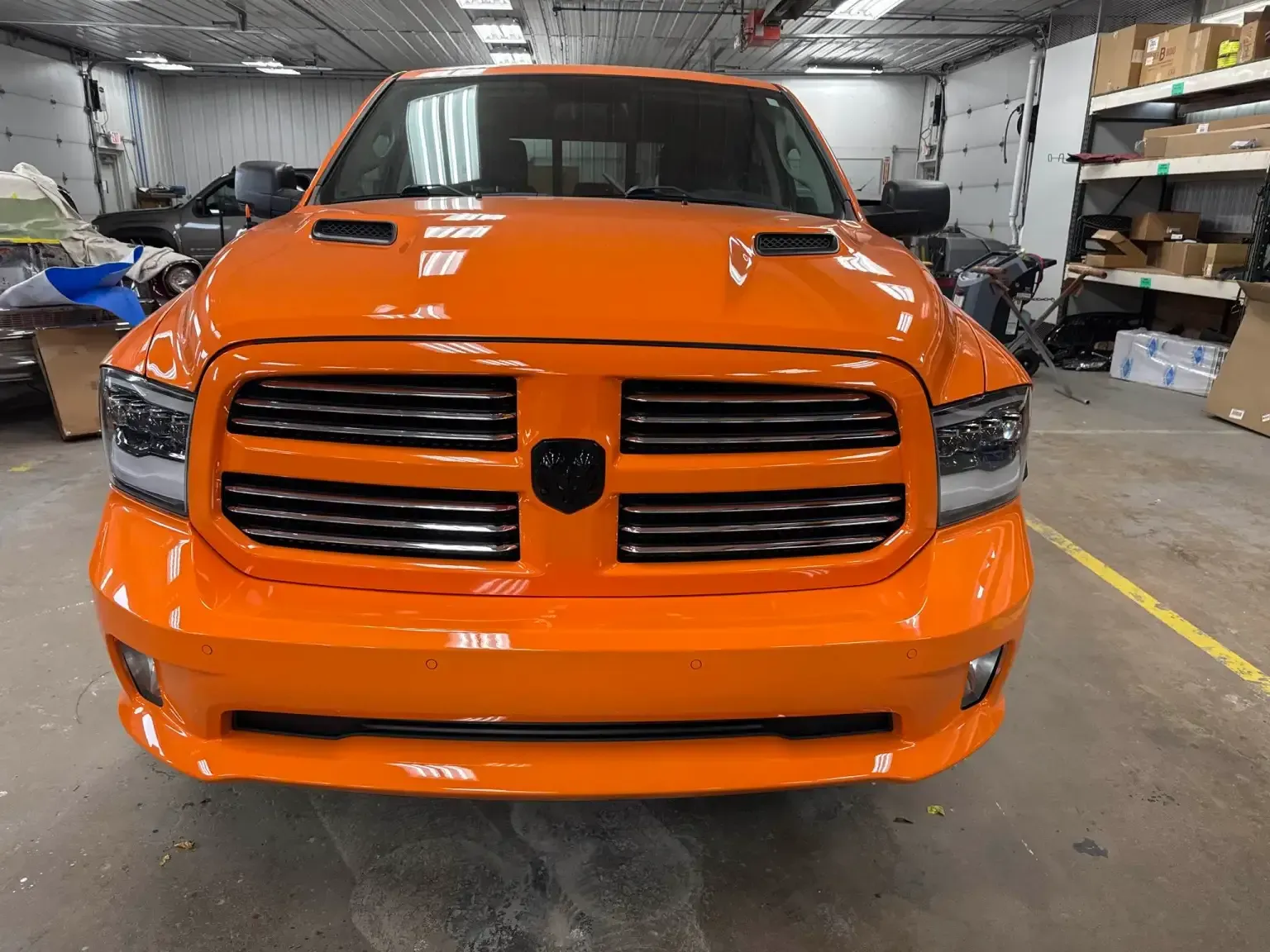 Bright orange Dodge Ram truck parked indoors, facing forward.