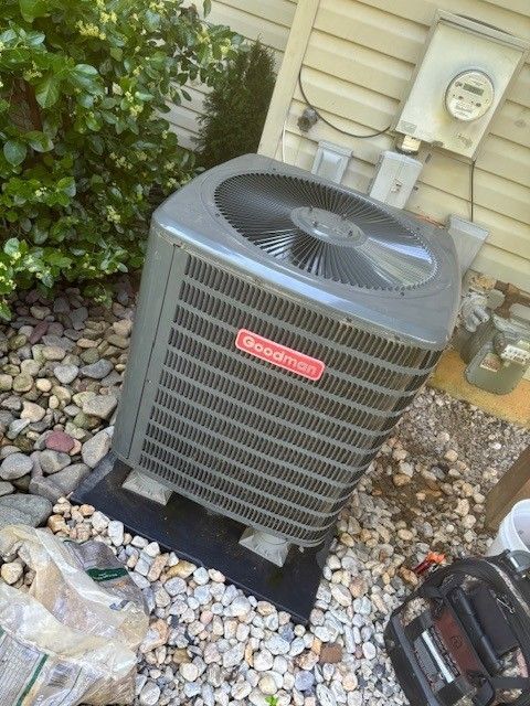 Outdoor air conditioning unit on a concrete pad, near a tan house.