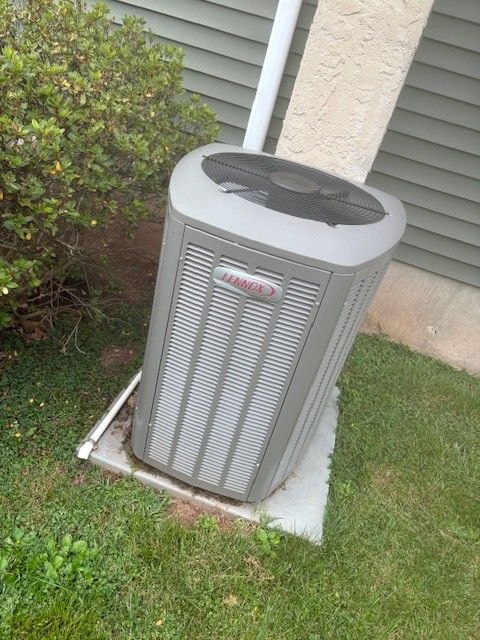 Two air conditioning units outside a house, on a concrete pad.