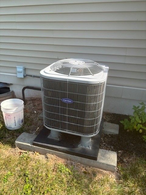 Two gray air conditioning units on a wooden platform outside a stone building.