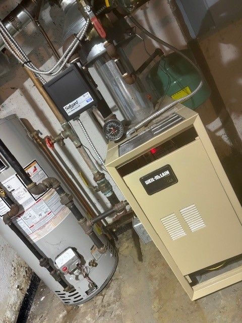 Person fixing a heating system, using tools and inspecting components.