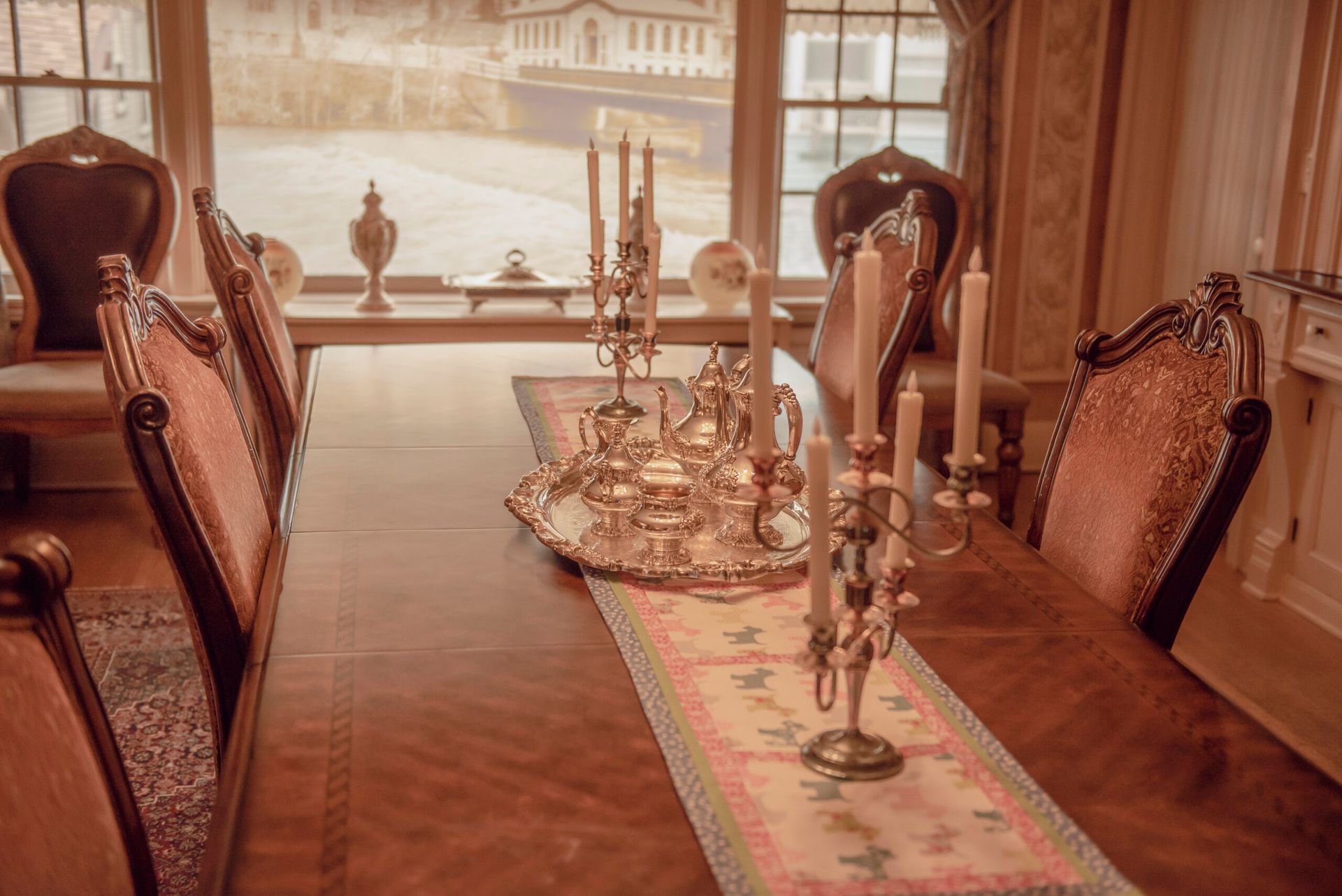 There are many candles on the table in the dining room.