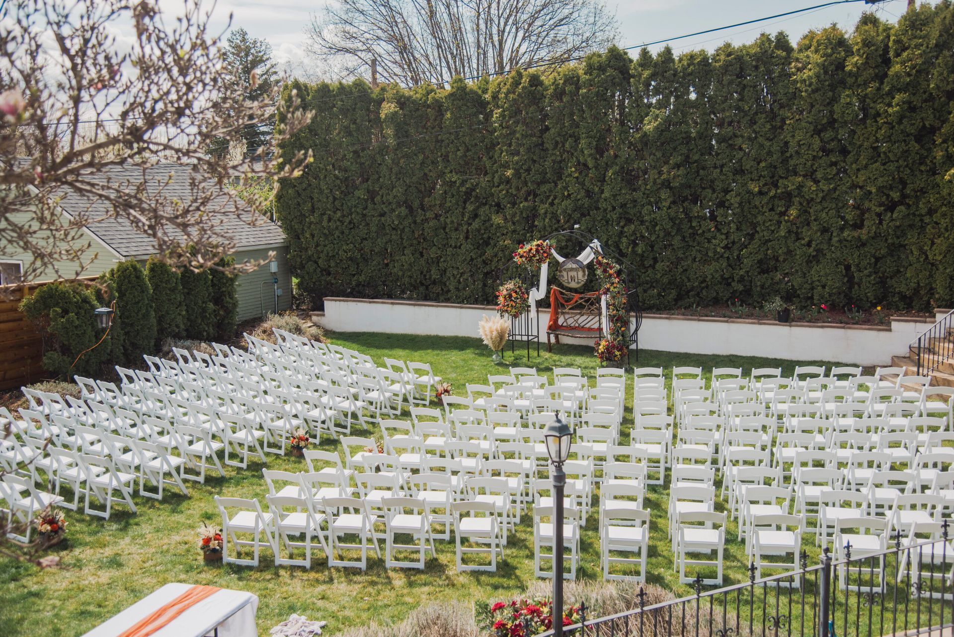 A row of white folding chairs are lined up in a grassy area.