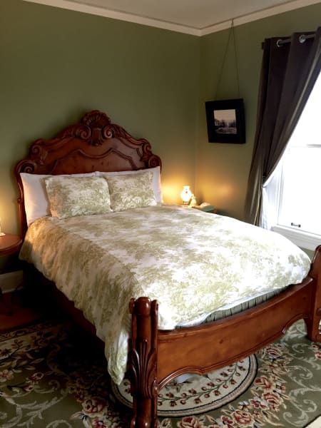 A bedroom with a bed and a window with a picture on the wall.