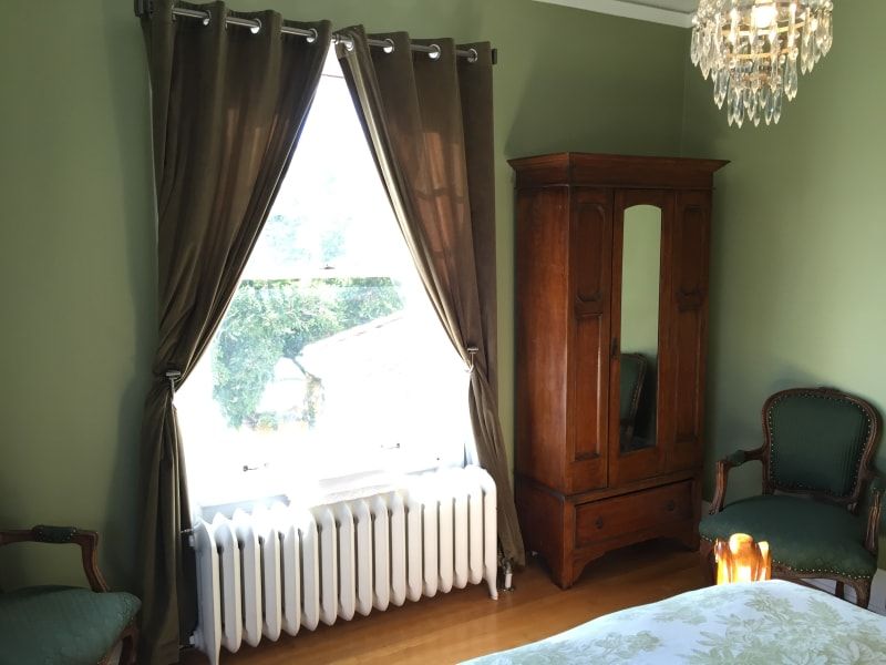 A bedroom with a large window and a chandelier