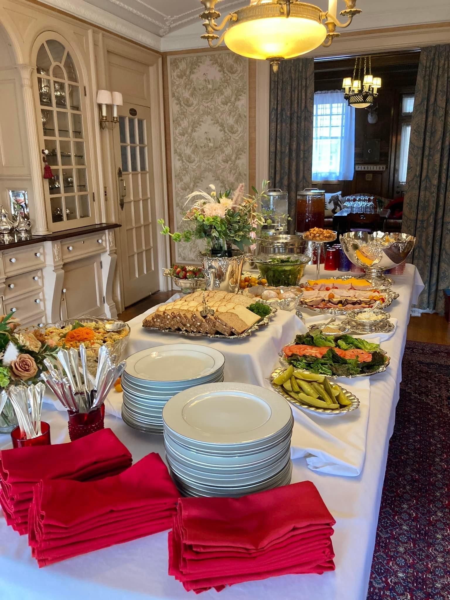 A buffet table with plates , napkins , and utensils on it.