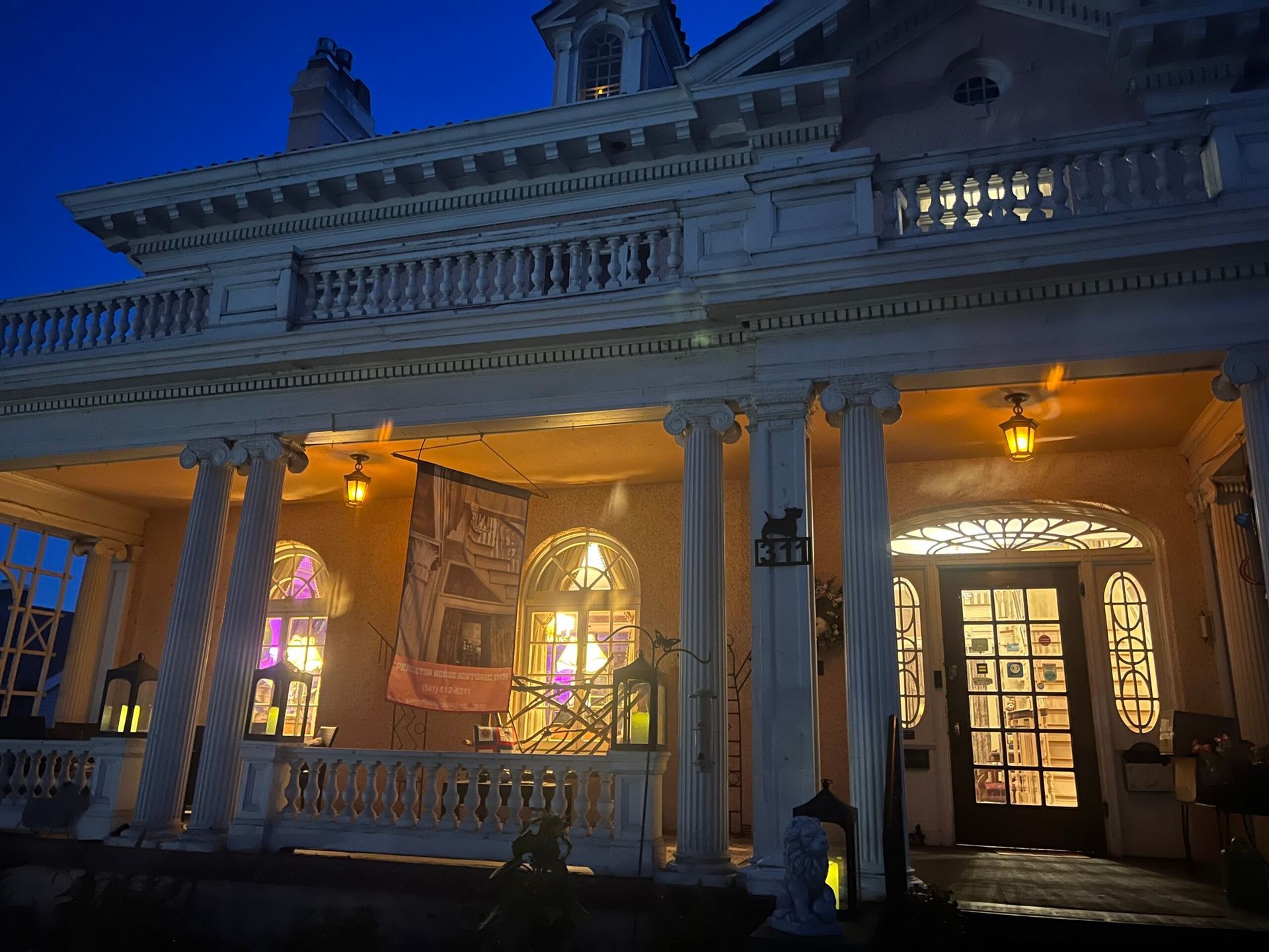 A large house with a porch and columns is lit up at night.
