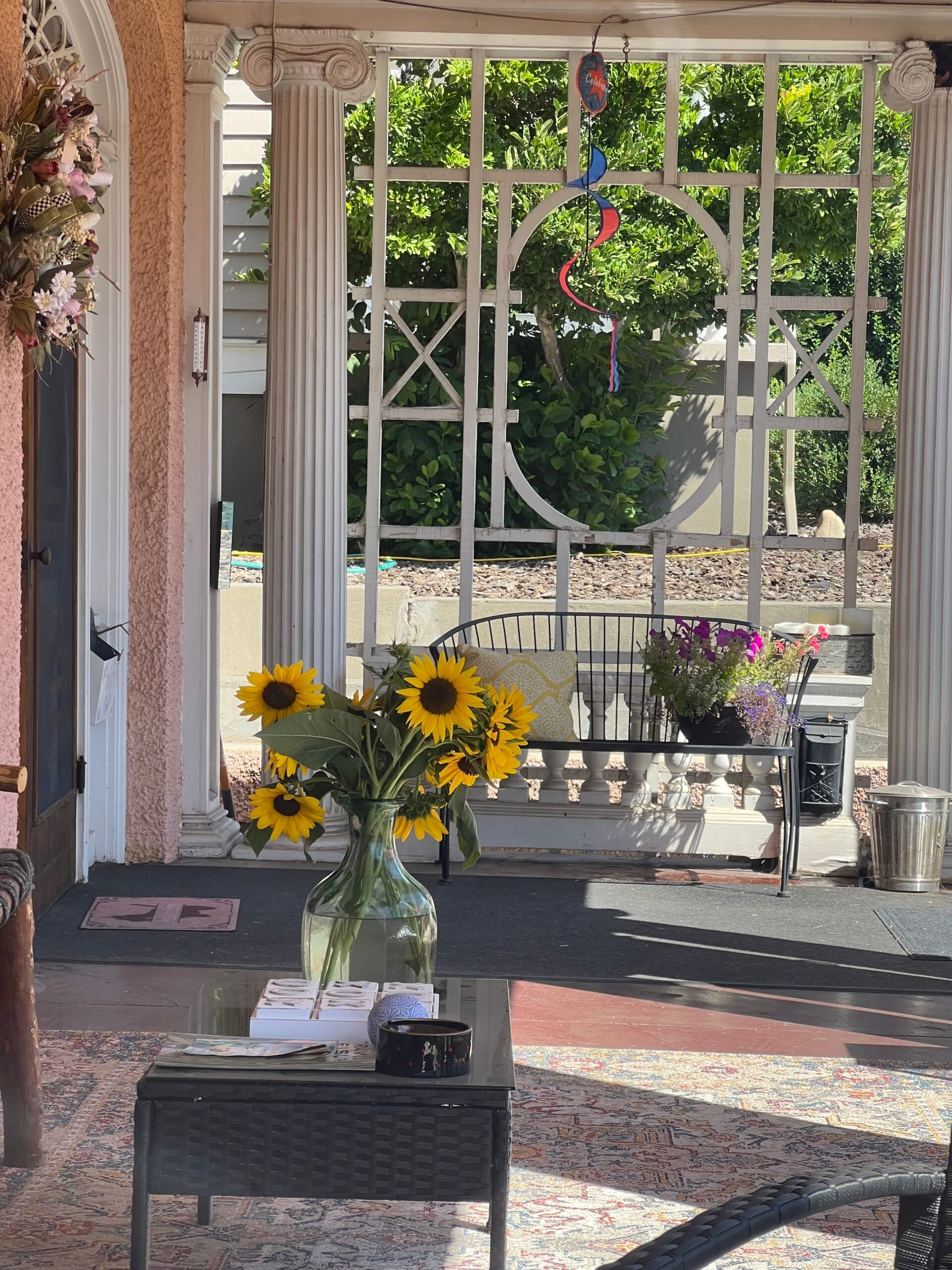 A vase of sunflowers sits on a table in front of a screened in porch