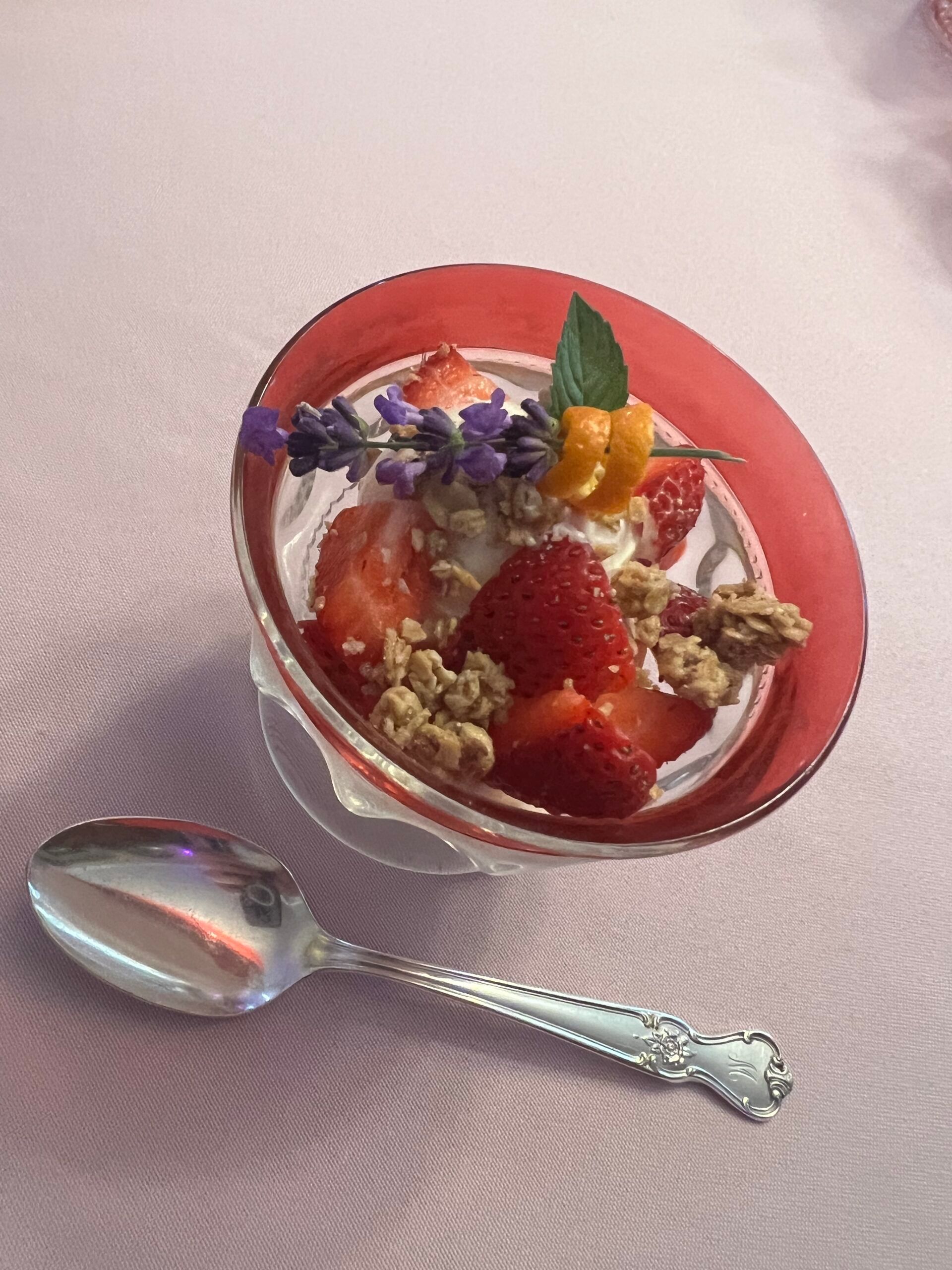 A bowl of strawberries and granola with a spoon in it