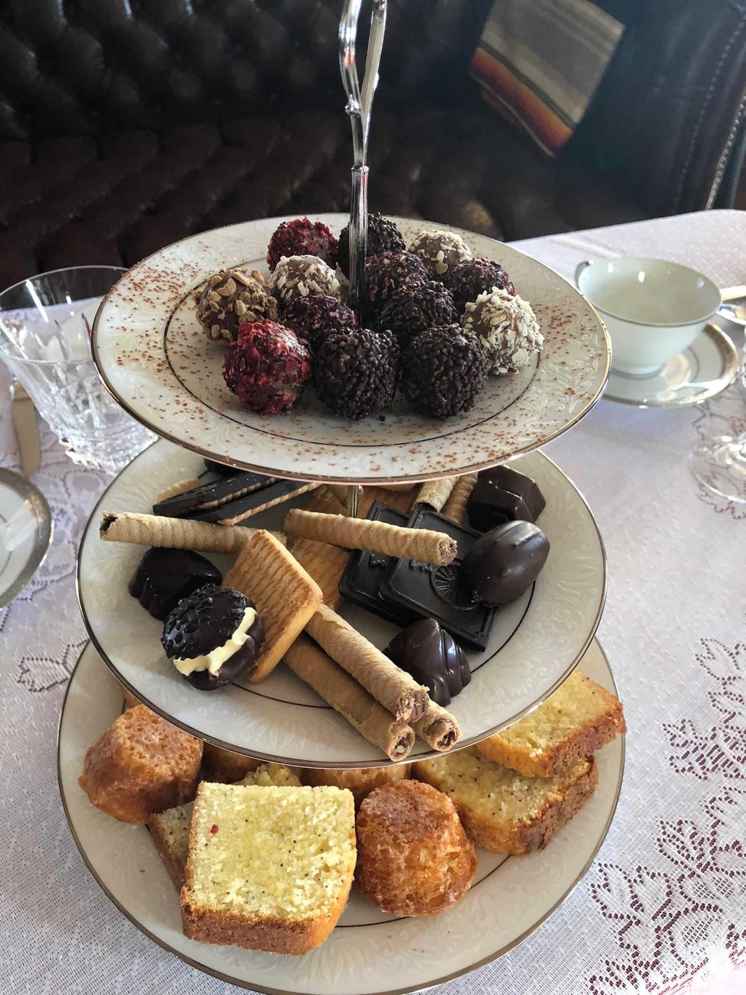 A three tiered cake stand filled with a variety of desserts on a table.