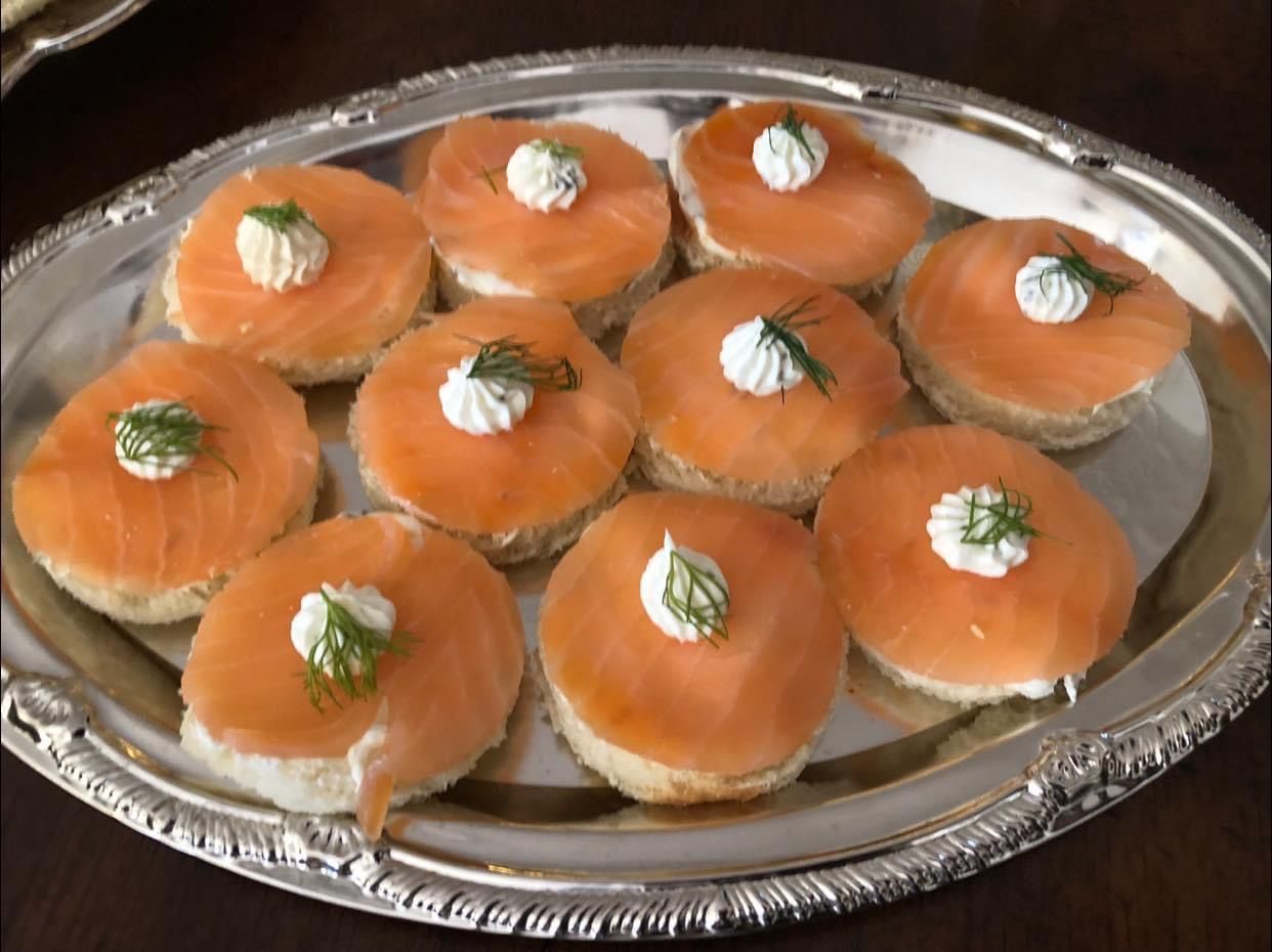 A silver plate topped with slices of smoked salmon and whipped cream.