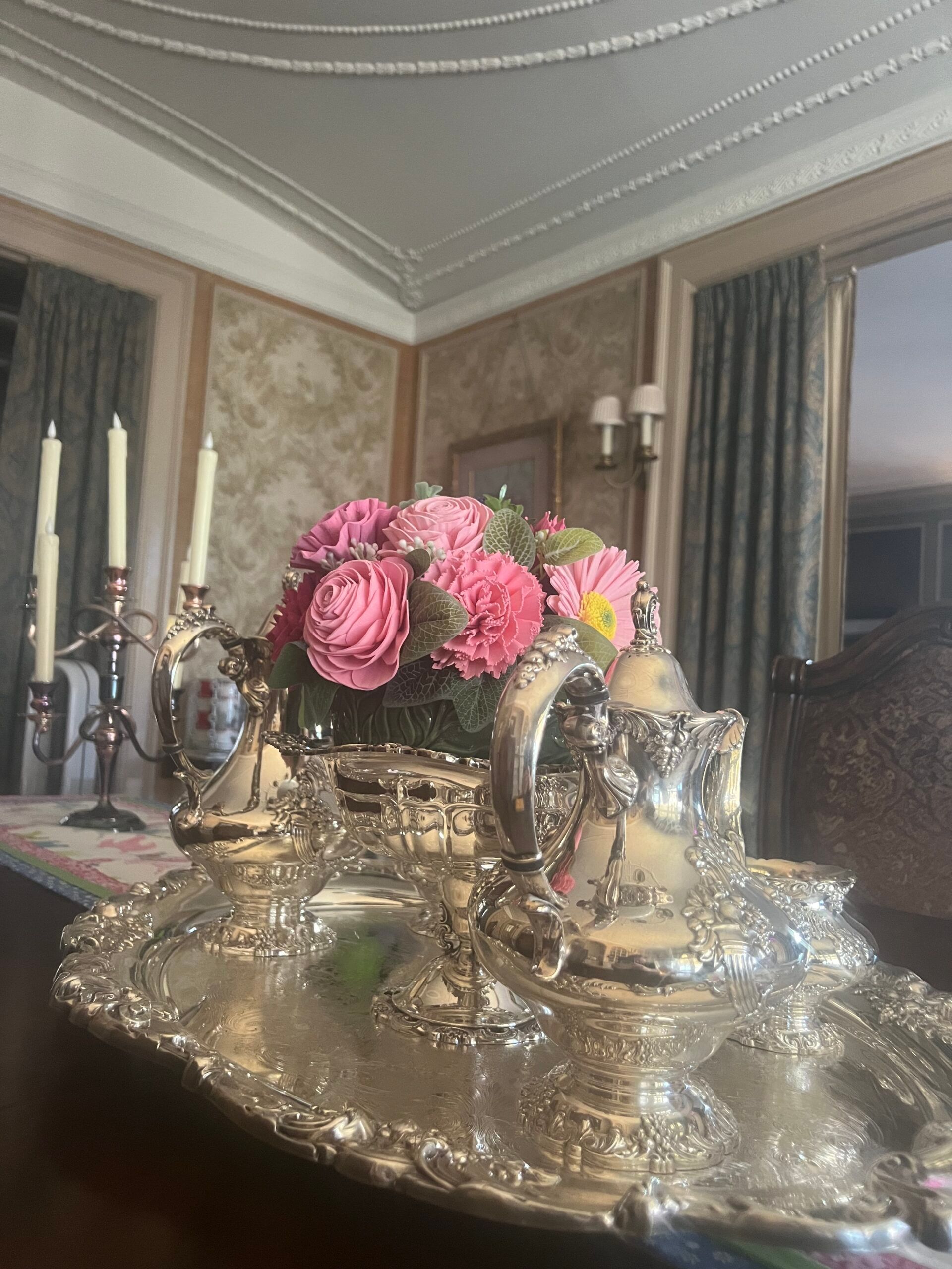 A silver tray with a vase of pink flowers on it