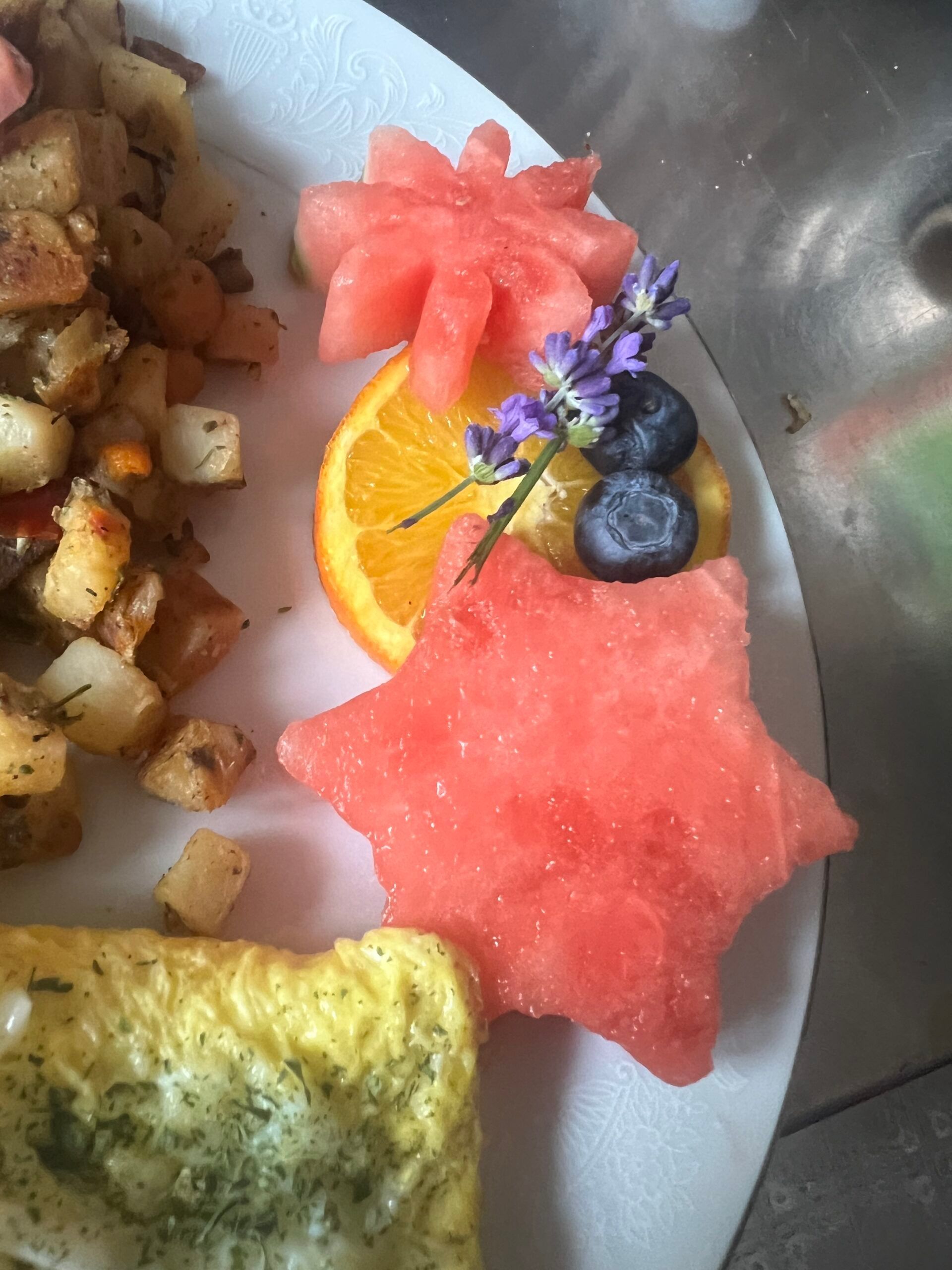 A plate of food with watermelon , blueberries , and an orange slice
