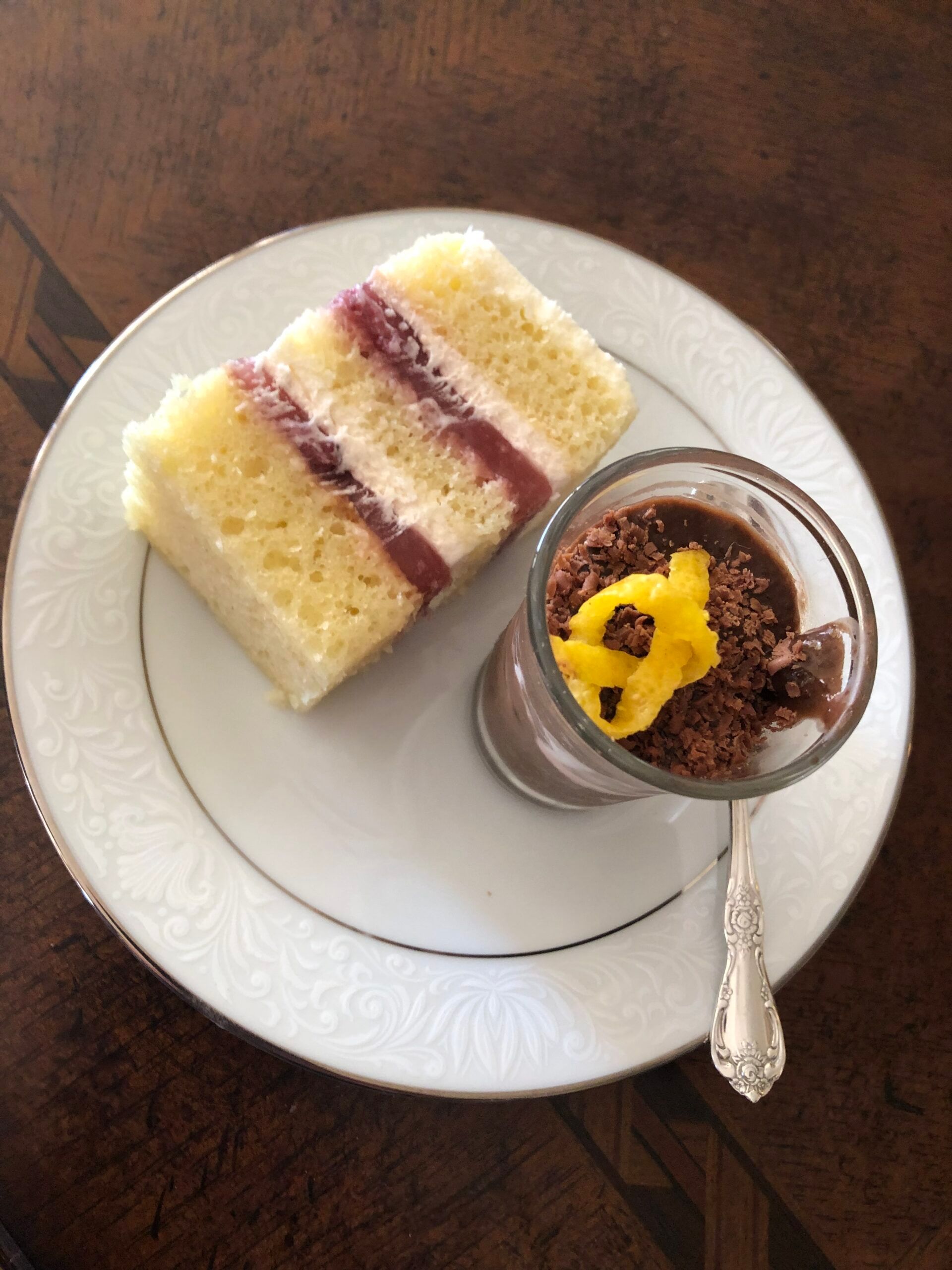 A white plate topped with a slice of cake and a cup of chocolate mousse