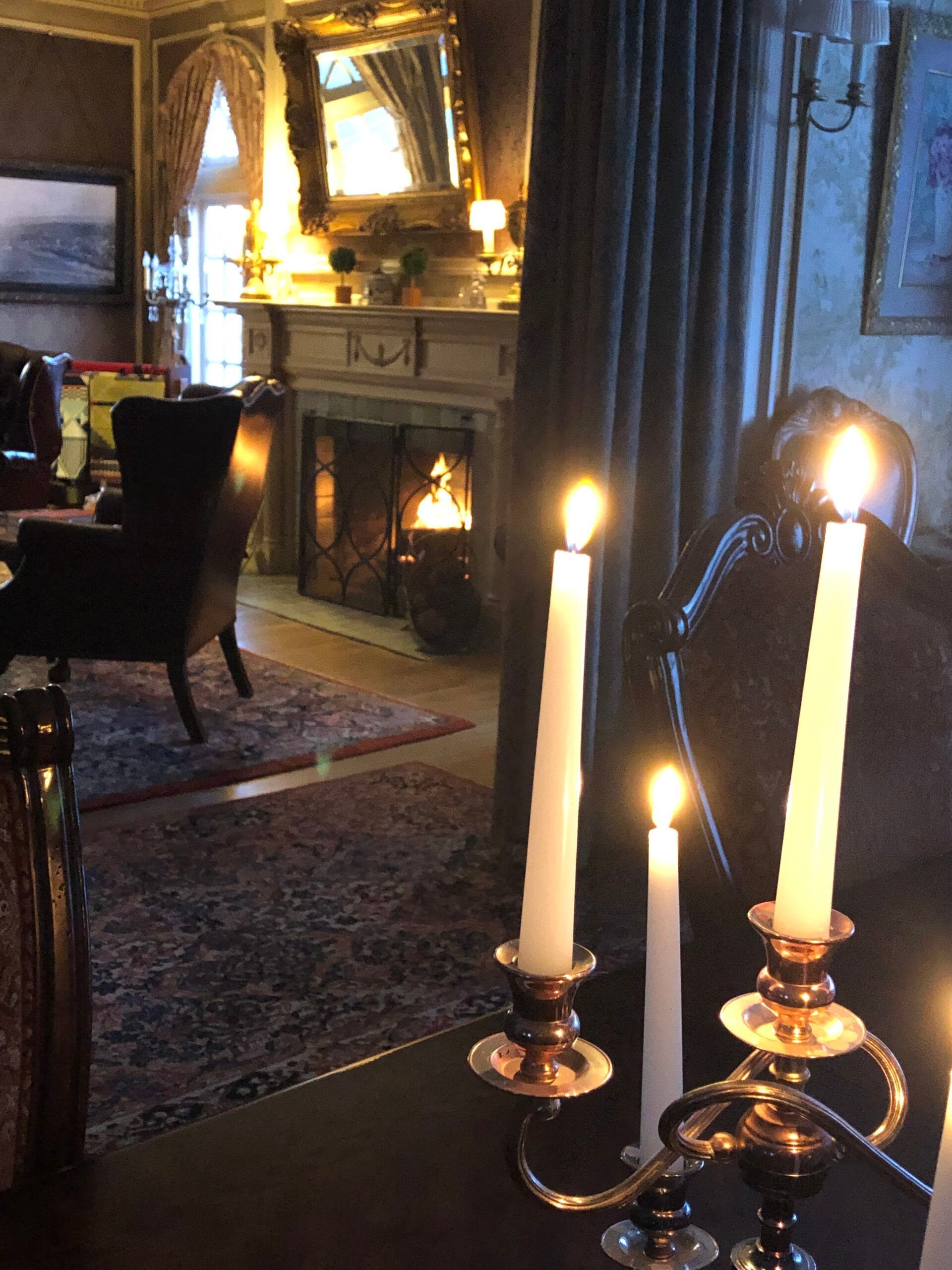 Candles are lit in a living room in front of a fireplace