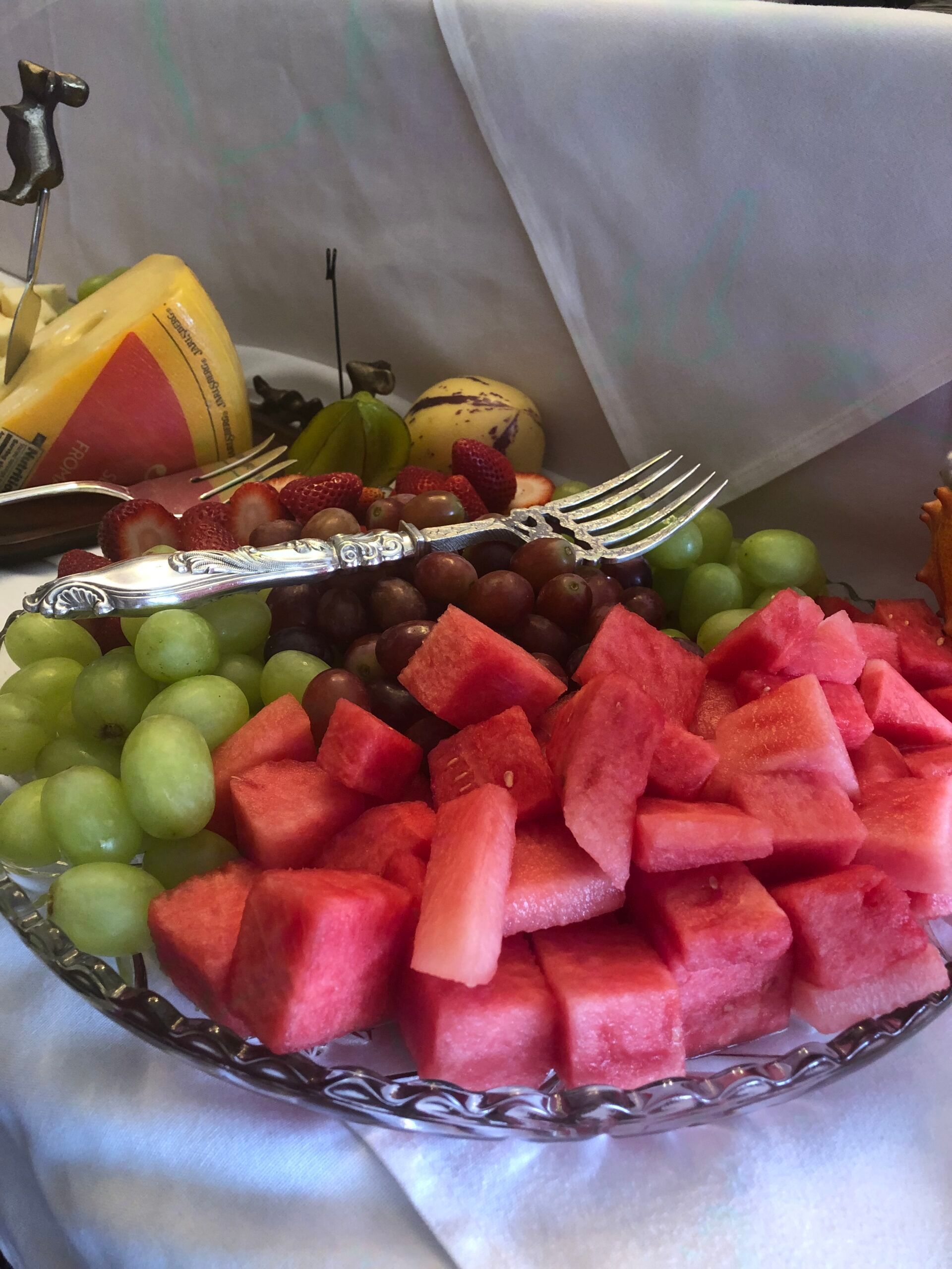 A plate of watermelon grapes and cheese on a table
