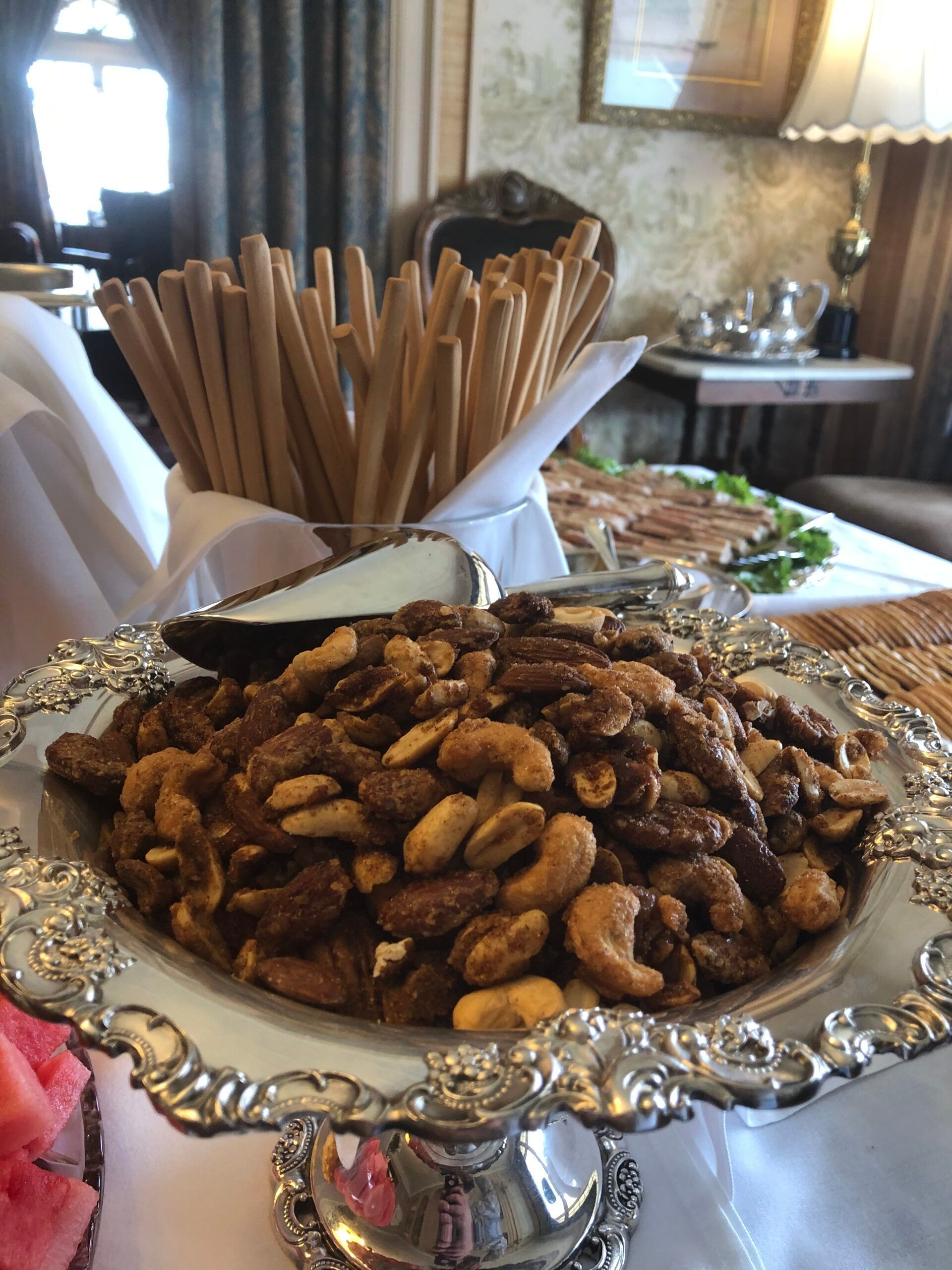 A silver plate filled with nuts and bread sticks on a table.