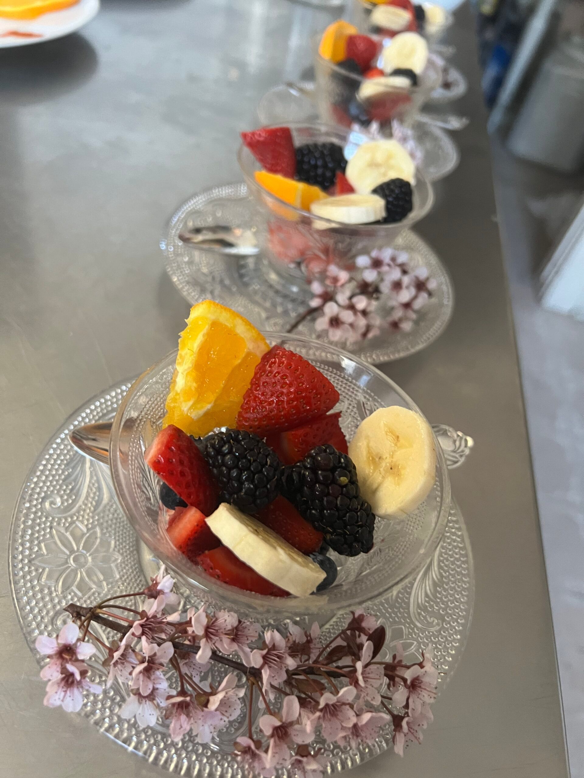 A row of bowls filled with fruit and flowers on a table