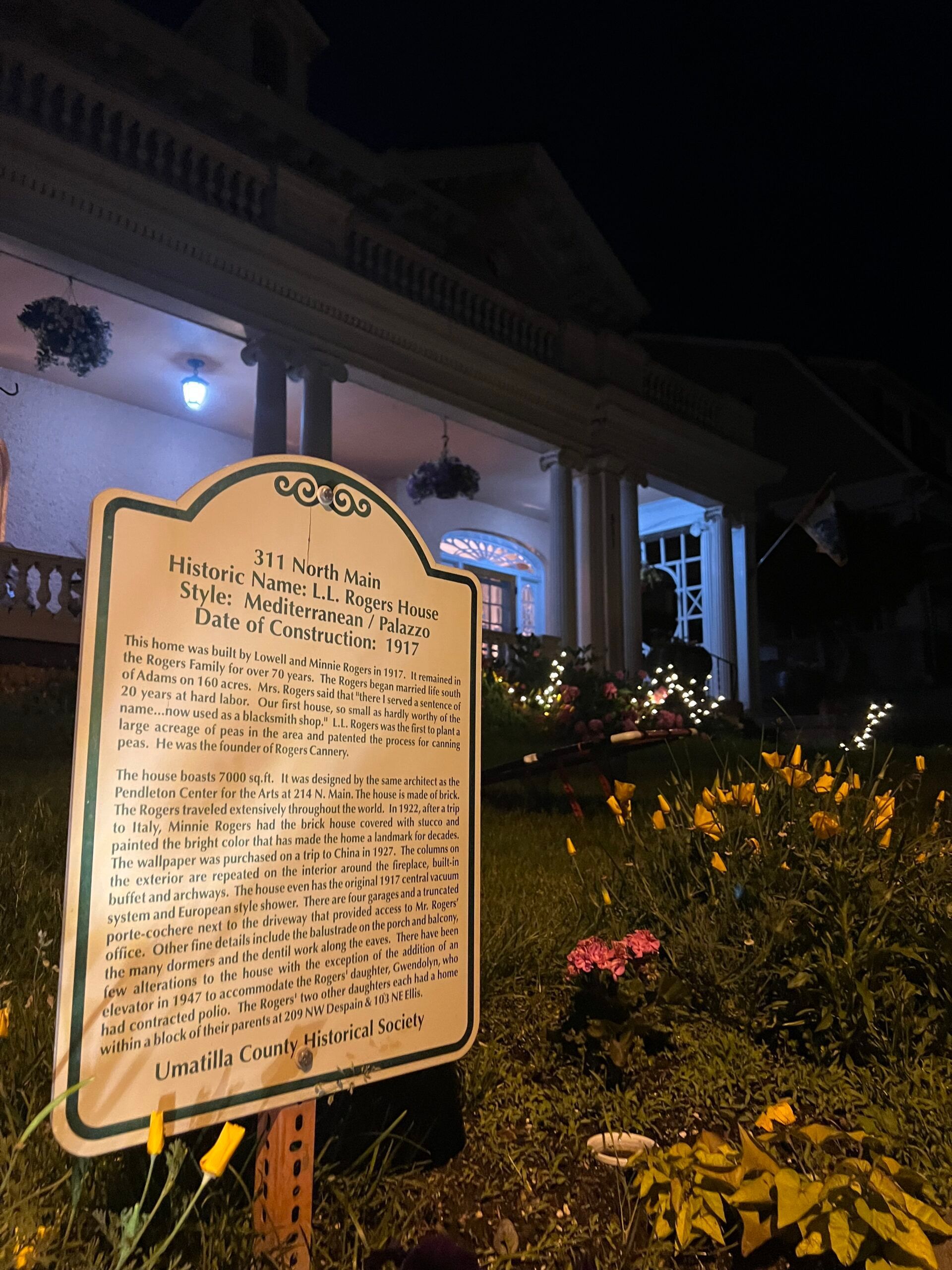A historical marker in front of a house at night