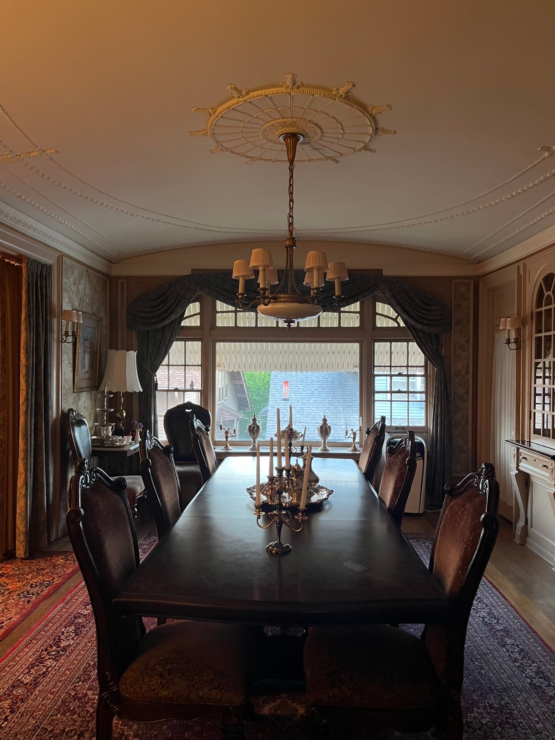 A dining room with a long table and chairs and a chandelier hanging from the ceiling.