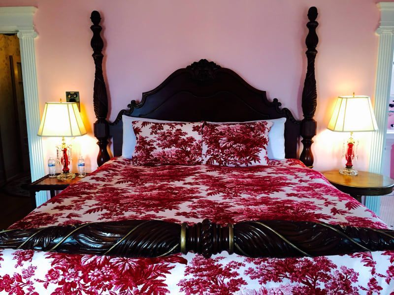 A bed with a red and white floral comforter and pillows