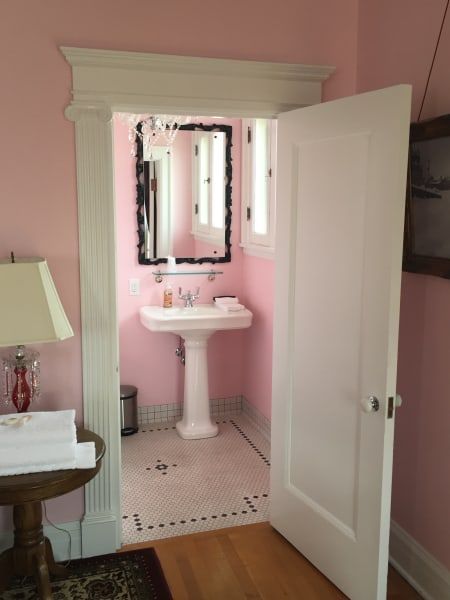 A bathroom with pink walls and a pedestal sink