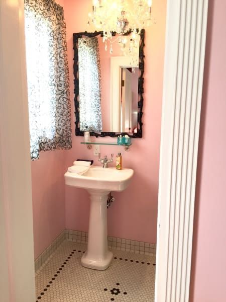 A bathroom with pink walls and a pedestal sink