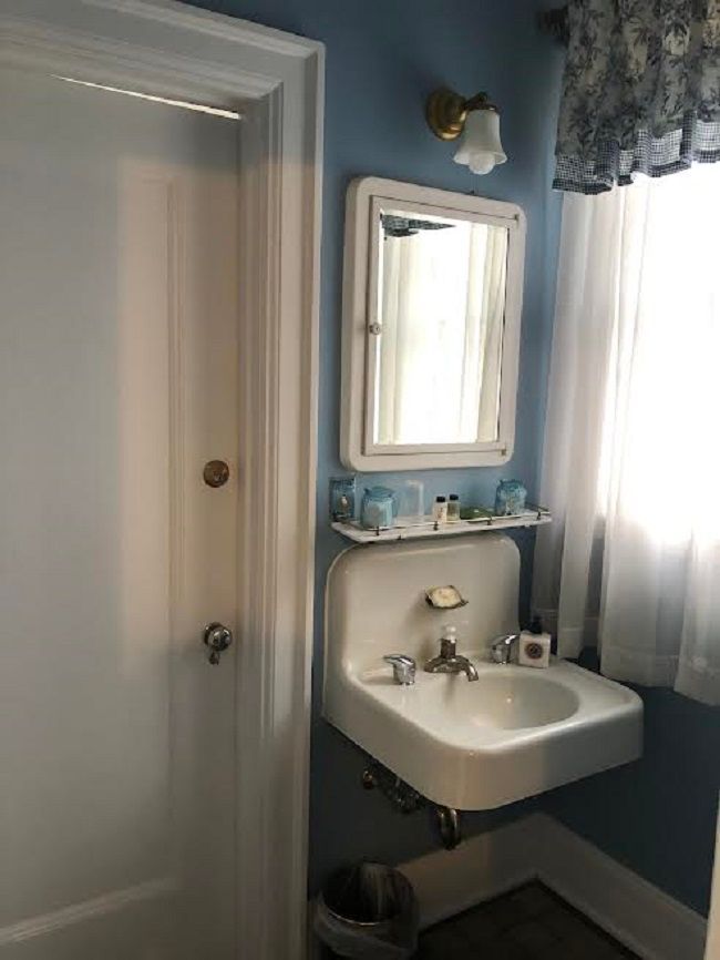 A bathroom with a sink , mirror and window.