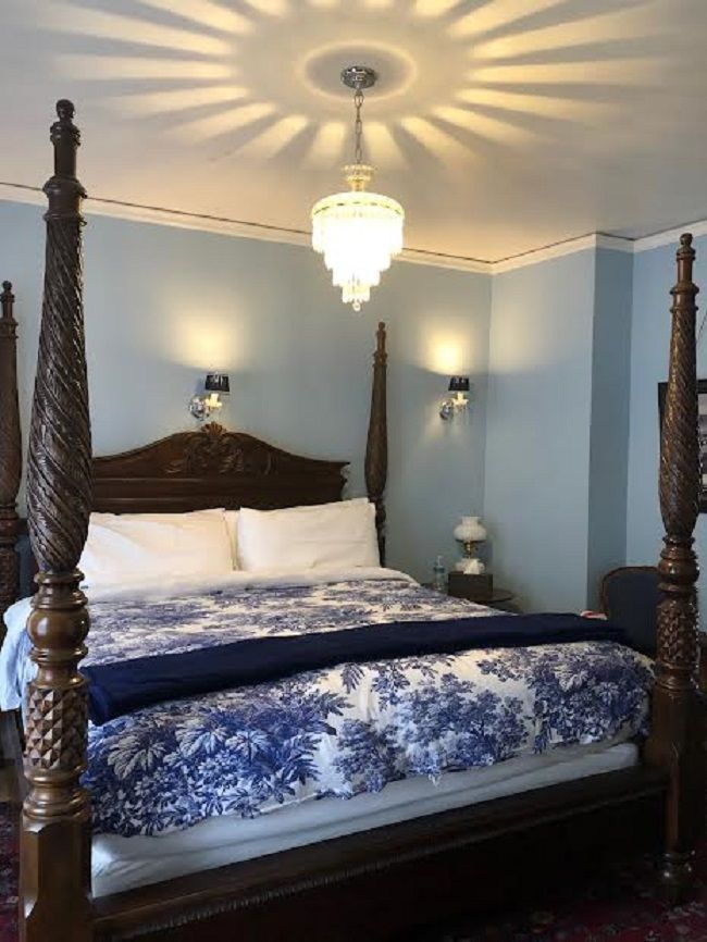A bedroom with a four poster bed and a chandelier