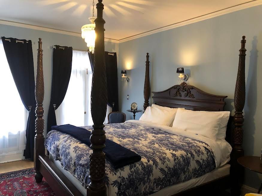 A four poster bed in a bedroom with blue and white sheets