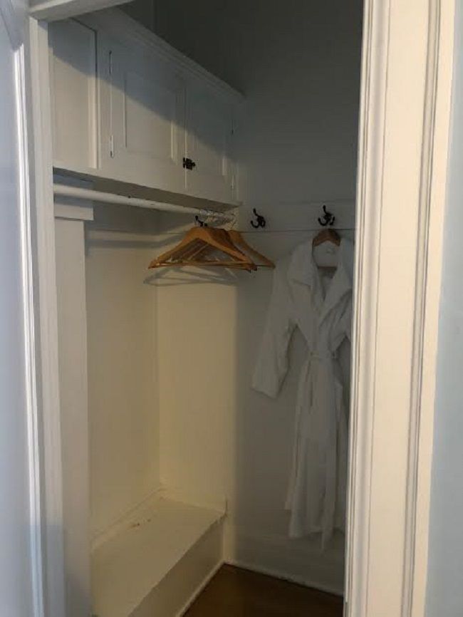 A closet with a white robe hanging on a hook.