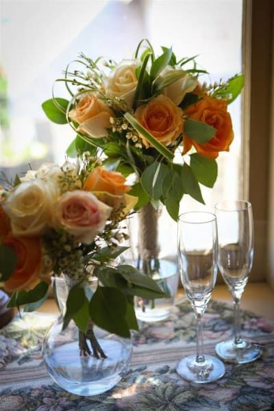 A vase of flowers sits on a table next to wine glasses